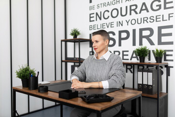 a young businessman in a strict gray suit enjoys listening to music on headphones against the background of an office wall