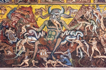 Close-up on religious mosaic decorating catholic church in Florence showing a demon eating people...