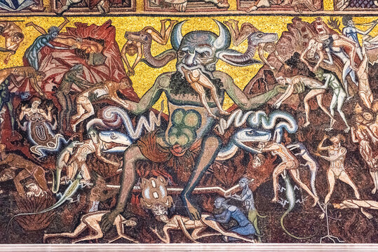 Close-up on religious mosaic decorating catholic church in Florence showing a demon eating people in hell