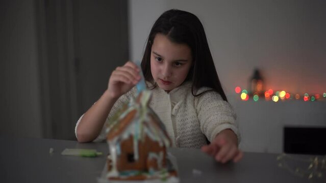 Little girl decorating gingerbread house for Christmas