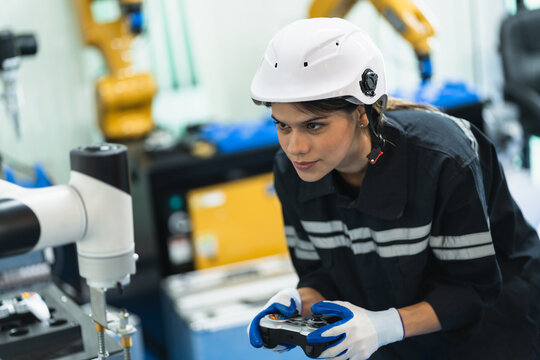 Engineer caucasian woman control  arm robot with remote in the machine lap 