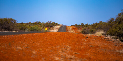 a road with a red shoulder in a remote area in karijini national park in western australia, red...