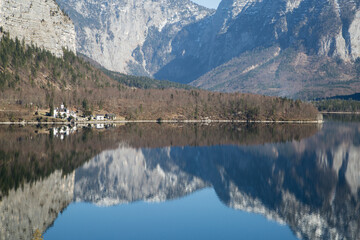 European lakeside village surrounded by mountains with mirrored reflection on the lake