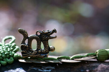 Dragon figurine with Chinese coins close-up on a colored background. East Asian culture. A spiritual symbol.