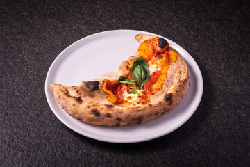 calzone pizza, folded stuffed pizza, italian food on a dark background