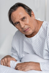 Fototapeta premium Senior patient looking at camera while sitting on hospital bed.