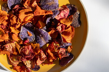 Organic vegetable chips. Close-up of orange and red carrot and beet chips on a plate.