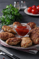 Cutlets of turkey fillet and oatmeal, fried in a pan, served with tomato sauce on gray table