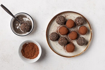 Dates, chia seeds and cacao bliss balls on ceramic plate. Healthy vegan raw dessert. top view