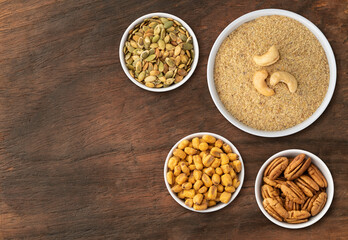 Assorted nuts and seeds with cashew nut flour over wooden table with copy space