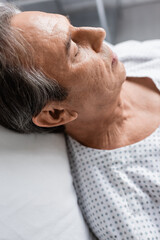 Fototapeta premium Elderly patient lying on blurred bed in hospital ward.