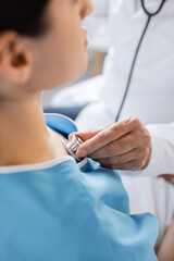 Cropped view of blurred doctor checking lungs of patient in hospital.