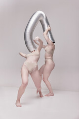 Weird expression. Creative photography with two young girls posing in nude underwear over beige...