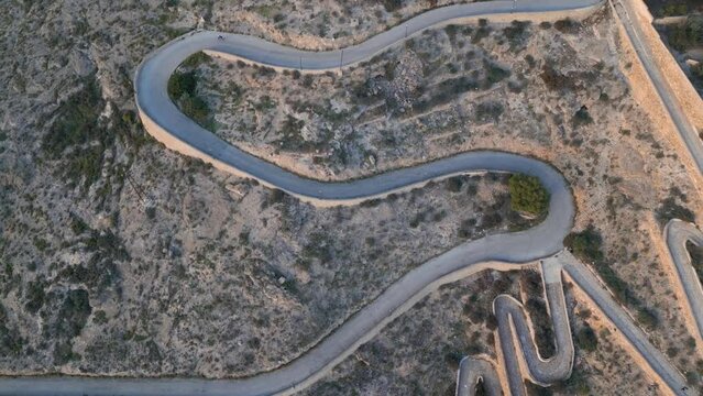 Cyclist athlete descending on road bike on a serpentine road in Orihuela, Spain. Sport mood motivational aerial video. 4k drone footage Top view Orihuela, Spain