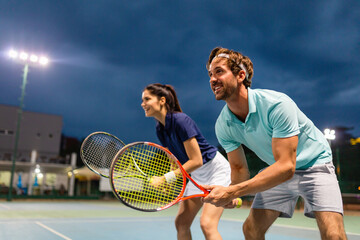 Young couple on tennis court. Handsome man and attractive woman are playing tennis.