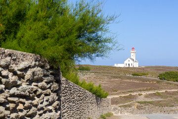 Poulains lighthouse on the hill with stone rustic wall on the foreground in Brittany, France