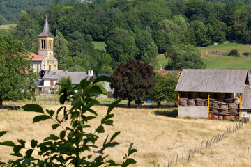 View at Moulis village at Ariege, Occitanie region of France in Pyrenees mountains. On the picture  we can see a field with the barn and Moulis church on the background.
