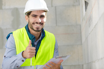 handsome construction worker with yellow jaket showing thumbs