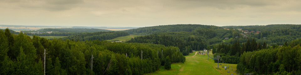 wide panoramic view from the top of a high hill to the mountainous wooded area of the ski resort in the summer