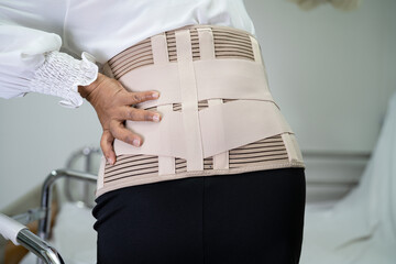 Asian lady patient wearing back pain support belt for orthopedic lumbar with walker.