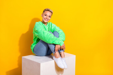 Full length photo of adorable satisfied person sit podium empty space isolated on yellow color background