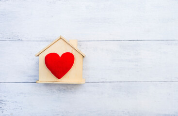 Red heart on wooden house model with space on white wood background, buy new house, property business