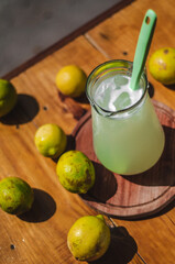 Jarra de limonada rodeada de limones en una mesa de madera