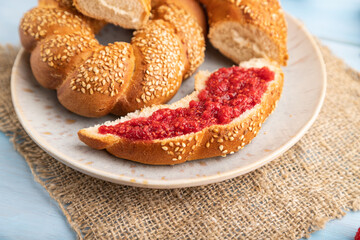 Homemade sweet bun with raspberry jam and cup of coffee on a blue wooden. side view, selective focus.