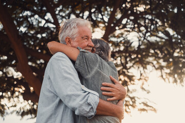 Head shot close up portrait happy grey haired middle aged woman snuggling to smiling older husband, enjoying tender moment at park. Bonding loving old family couple embracing, feeling happiness..