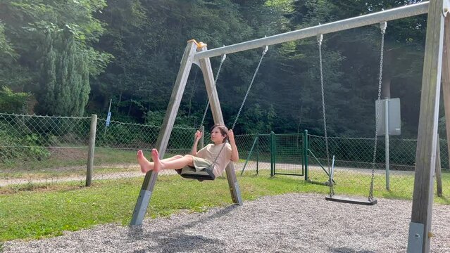 Carefree caucasian boy having fun on swing at park