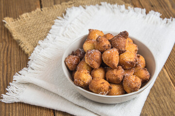 Homemade Castagnole, typical italian carnival fritters with sugar in a white bowl on rustic wooden table