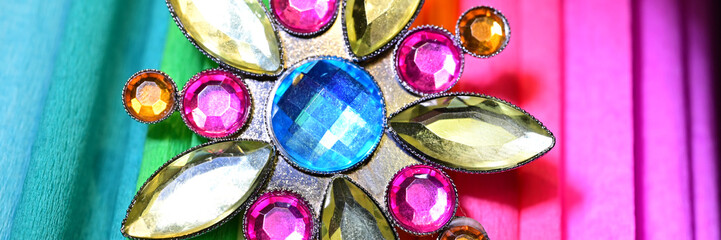 Fancy jewel brooch on colored paper, multicolored banner