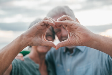 Close up portrait happy sincere middle aged elderly retired family couple making heart gesture with...