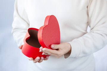 Female hands open a red heart shaped box. Happy Valentines Day gift box.