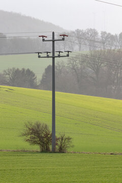 Strommast im Kalletal mitten auf einem Feld an einem nebligen Tag im Kalletal im Winter