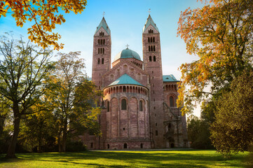 Der Dom in Speyer, weltbekannte Kathedrale, die Ostseite mit Park im Herbst, umrahmt von Bäumen - obrazy, fototapety, plakaty