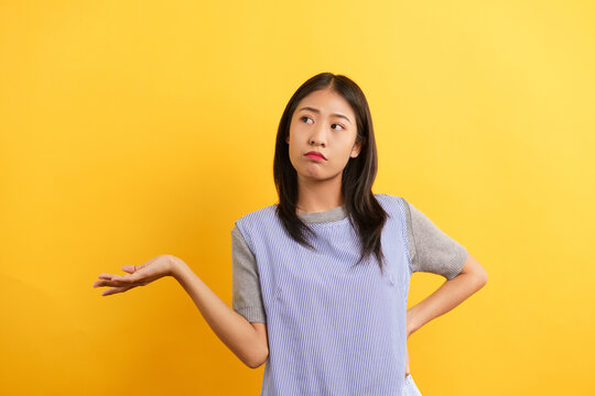 Young women making confused face and open one hand to asking why on isolated yellow background