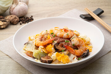 Stir Fried Brown Rice Vermicelli with Prawns ,eggs ,cabbage and dried shiitake mushrooms in white plate