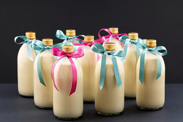 Homemade eggnog in bottles with blue and pink bows on dark background