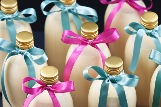 Homemade eggnog in bottles with blue and pink bows on dark background