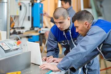two engineers looking at laptop in workshop