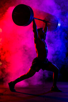 Muscular man doing snatch exercise with barbell