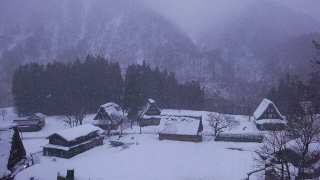 Snow and mist over traditional houses in rustic mountain village at dawn