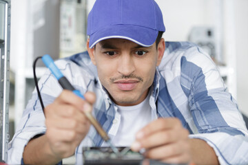 man testing circuit board in his office