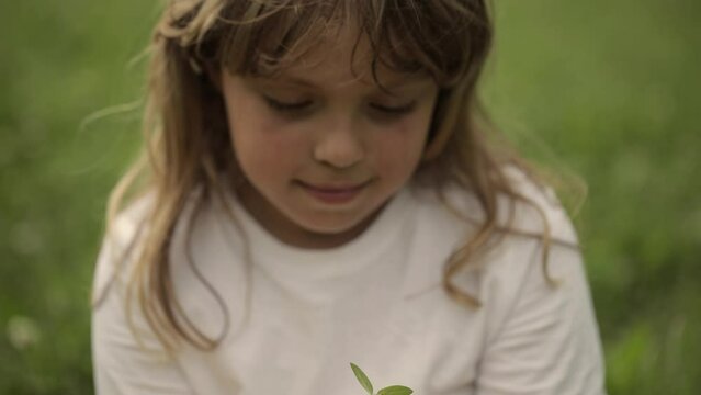 Caucasian girl is keeping a green seedling and soil in her hands