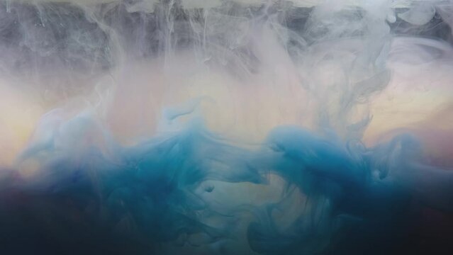 Blue colored ink burst in water and form an abstract smoke pattern