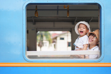 Happy Asian little boy and mother Laughing while traveling by train, Playful Child with big smile.