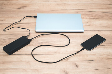 Power bank with usb-c cable is charging laptop and smartphone. Modern, information technology.