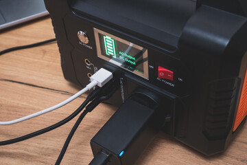 Naklejka premium lithium Portable Power Station is charging laptop smartphones.Power banks and other gadgets..Modern, information technology. Control panel. close up.
