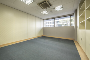 An empty office office with blue carpeted floors and filing cabinets with lockable doors